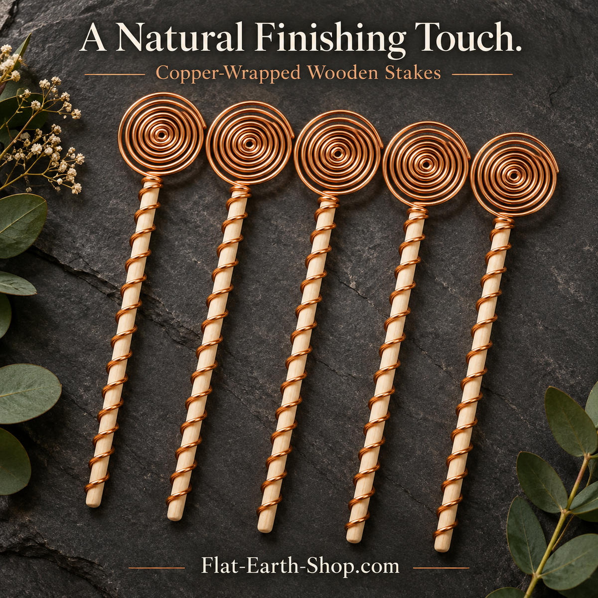Five wooden garden stakes wrapped in copper-colored wire, with circular spiral tops, arranged on dark stone.