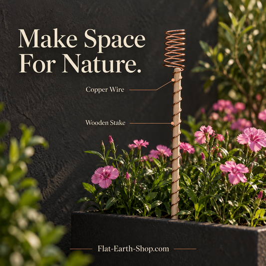 Wooden garden stake wrapped in copper-colored wire, with a spring-shaped top, among pink flowers in a planter.