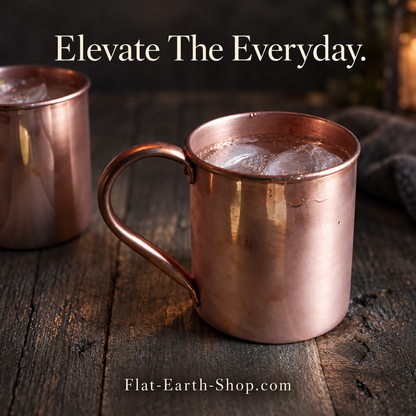 Copper-colored mug filled with ice on a rustic wooden table, with a second mug partly visible behind it.