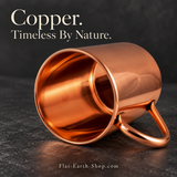 Smooth copper-colored mug lying on its side, showing its open interior and curved handle on a dark stone surface.