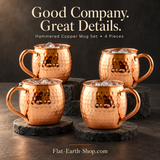 Four rounded, hammered copper-colored mugs filled with ice, arranged on dark stone platforms and round coasters.