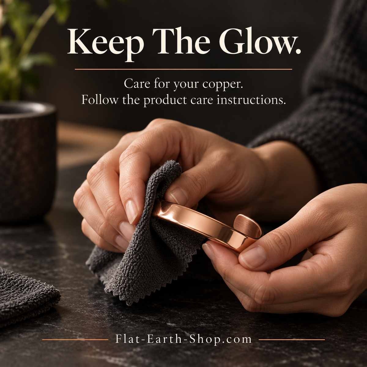 Hands polishing a copper-colored open cuff with a dark cloth on a stone countertop.