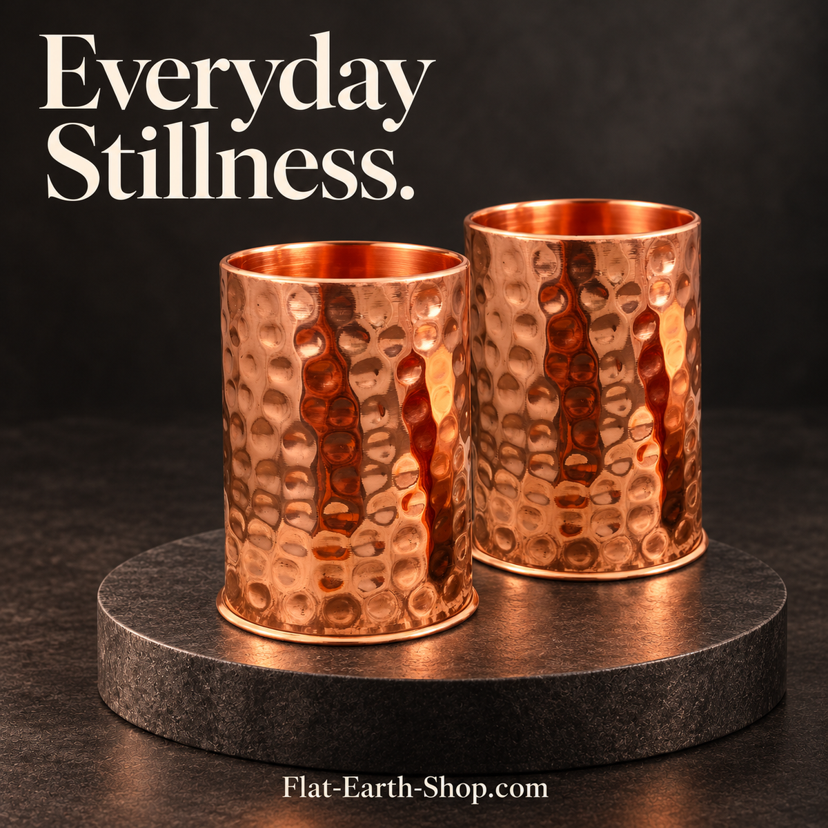 Two hammered copper cups on a dark stone pedestal