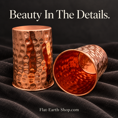 Hammered copper cup pair on charcoal linen with copper interior visible