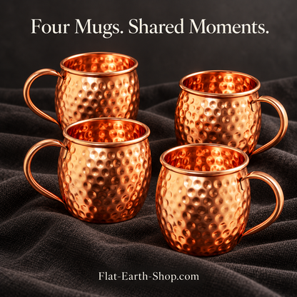 Four hammered copper mugs with curved handles in a dark studio scene