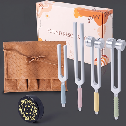 Two weighted and two unweighted tuning forks with pastel handles beside a brown pouch, black activator, and peach box.